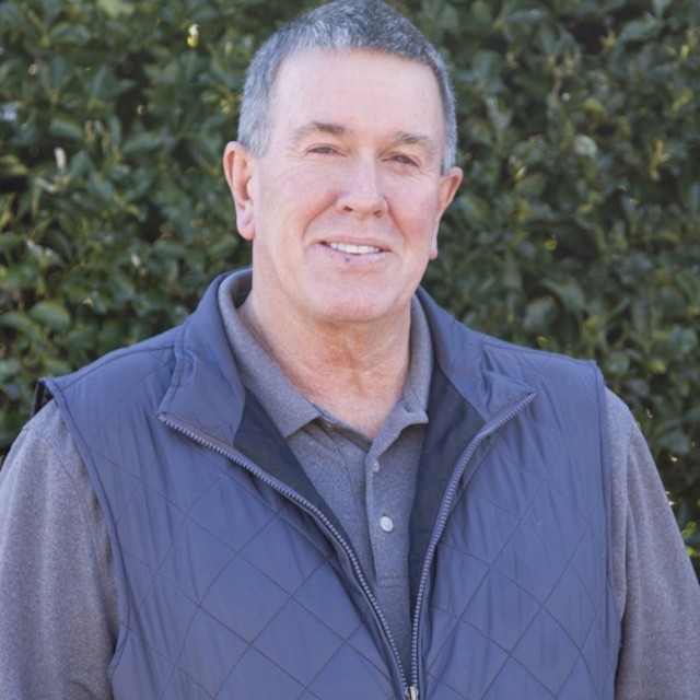 Barry Rowe headshot in front of green bush