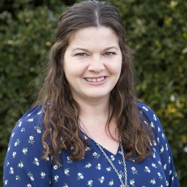 Heather Wise headshot in front of green bush