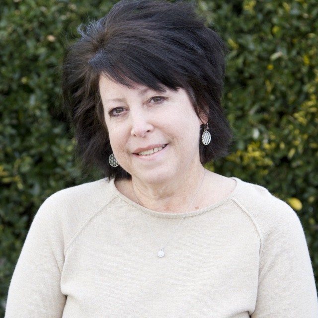 Lisa Armstrong headshot in front of green bush