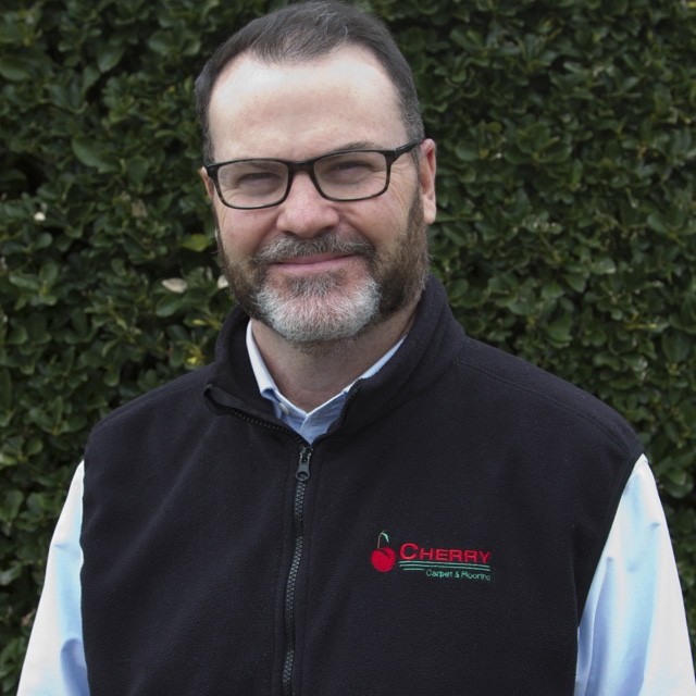 Mike Carroll headshot in front of green bush