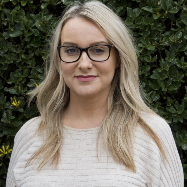 Nichole Modlin headshot in front of green bush