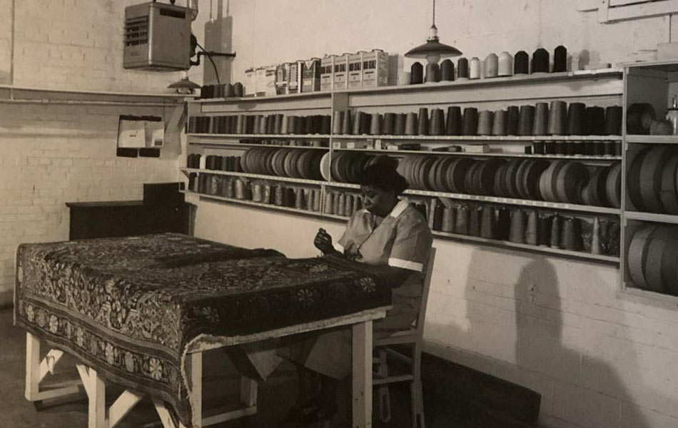 Black and white photo of woman working on an area rug