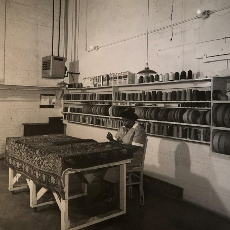 Black and white photo of woman working on an area rug