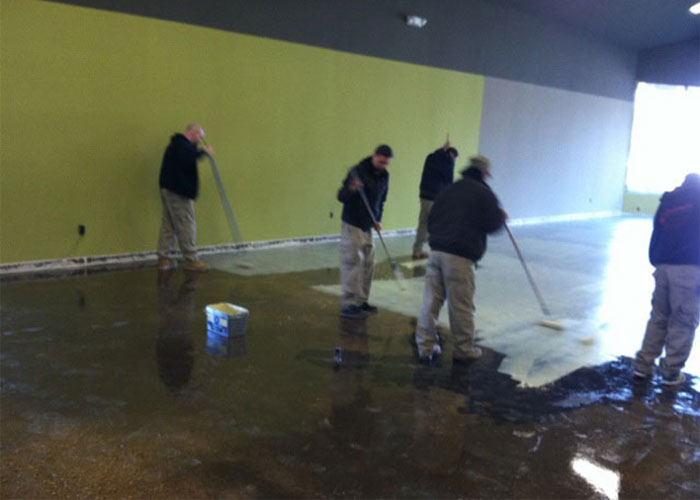 Group of flooring installers using moisture mitigation techniques in large commercial building