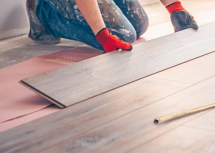 Flooring installer kneeling and placing in hardwood floors