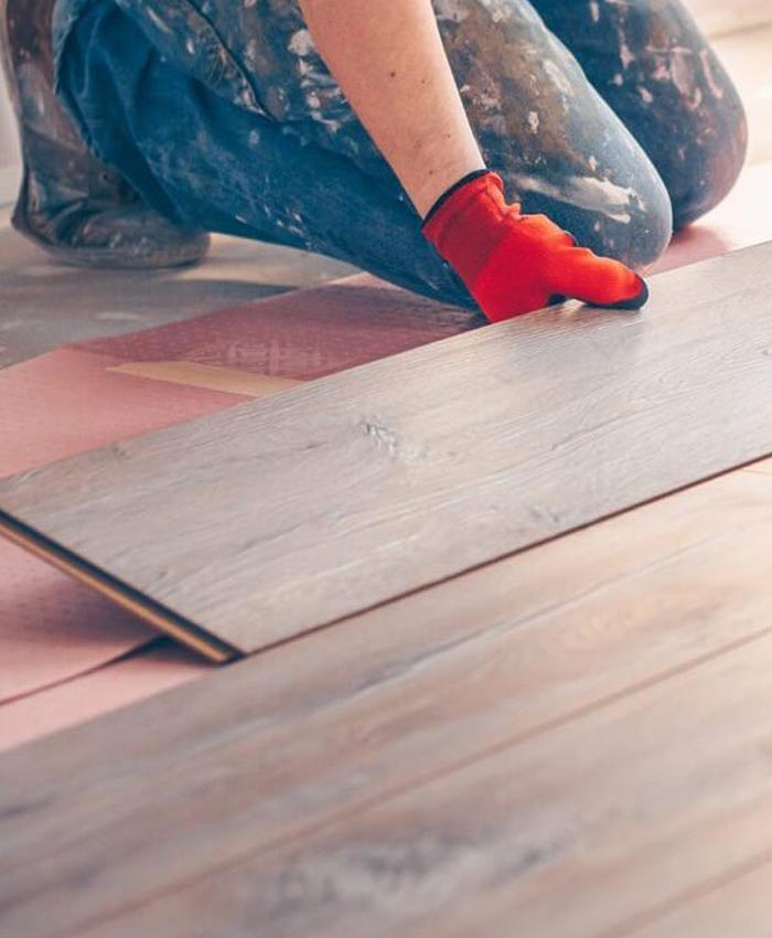 Flooring installer kneeling and placing in hardwood floors