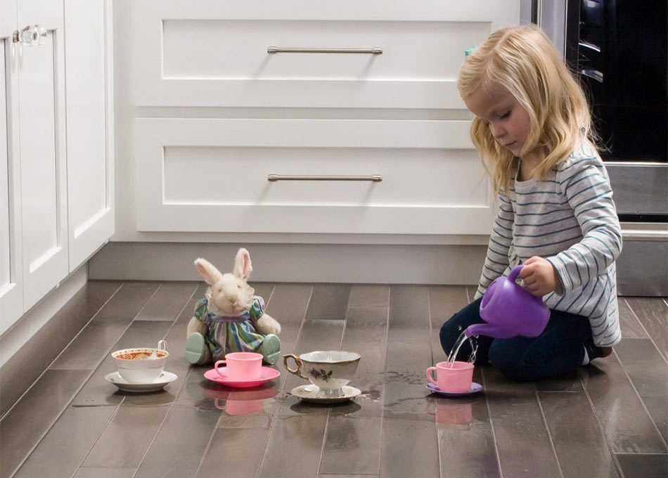 Young child tea party spill on dark luxury vinyl flooring