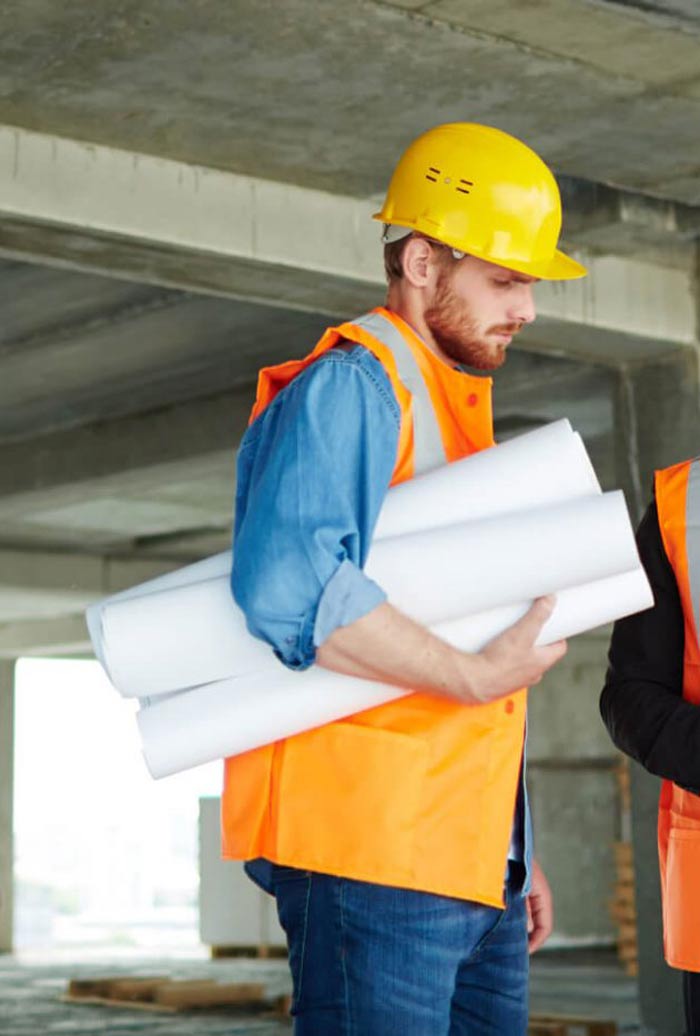 Construction worker wearing bright colors and hard hat holding plans