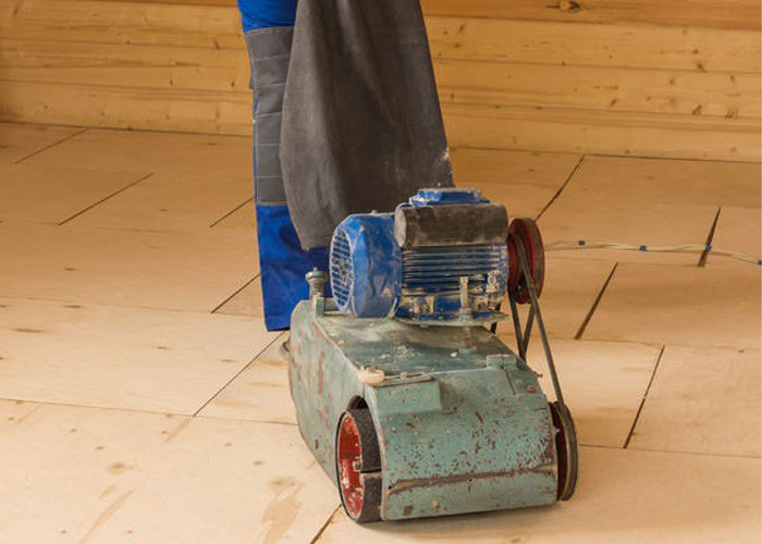 Installer preparing the subfloor for installation using power tool