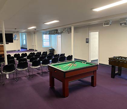 YOURS Ministry pool table, purple carpet, and chairs